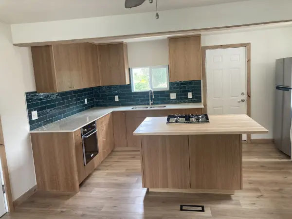 Cherry flat panel kitchen cabinets with a teal tile backsplash